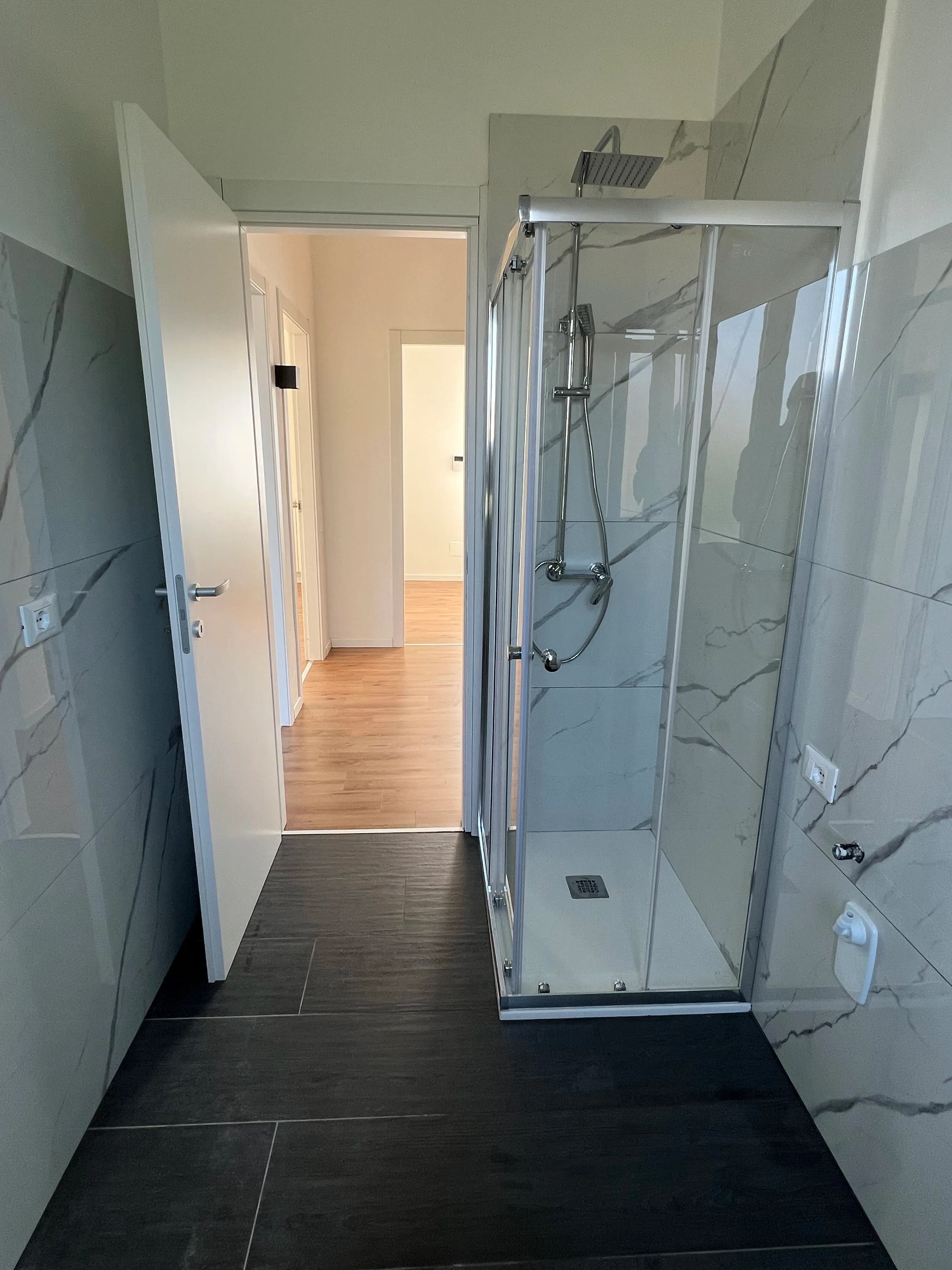 Bagno ristrutturato con doccia in vetro e piastrelle effetto marmo da Maestro Edilizia | Ristrutturazione Casa a Milano.